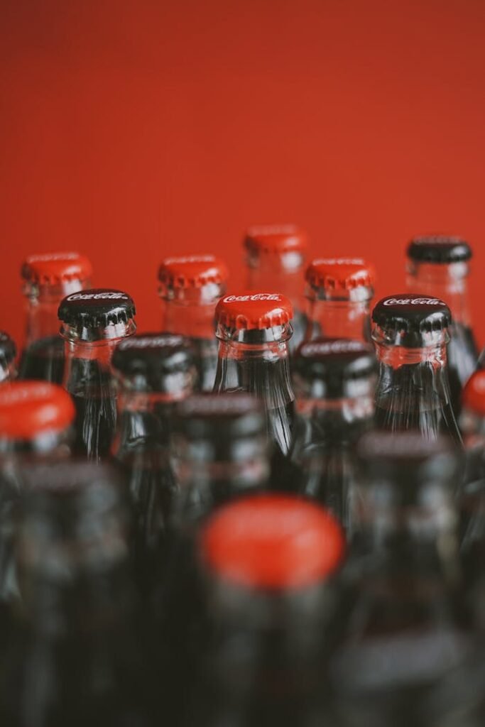 A close-up of Coca-Cola bottle tops with a focus on red caps against a red background.